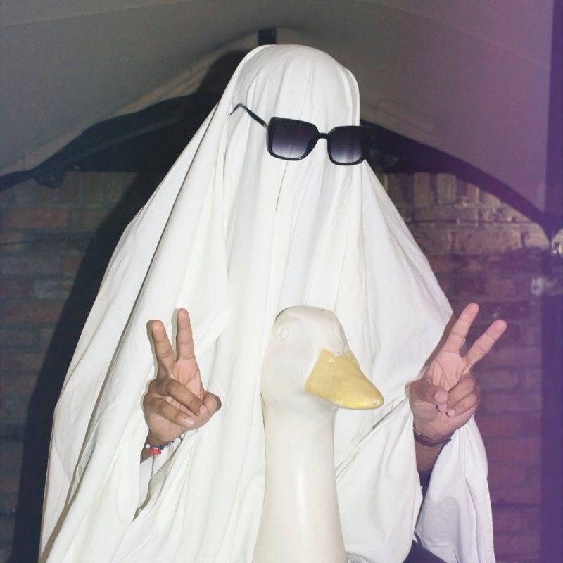 The ghost making peace signs next to a white duck statue