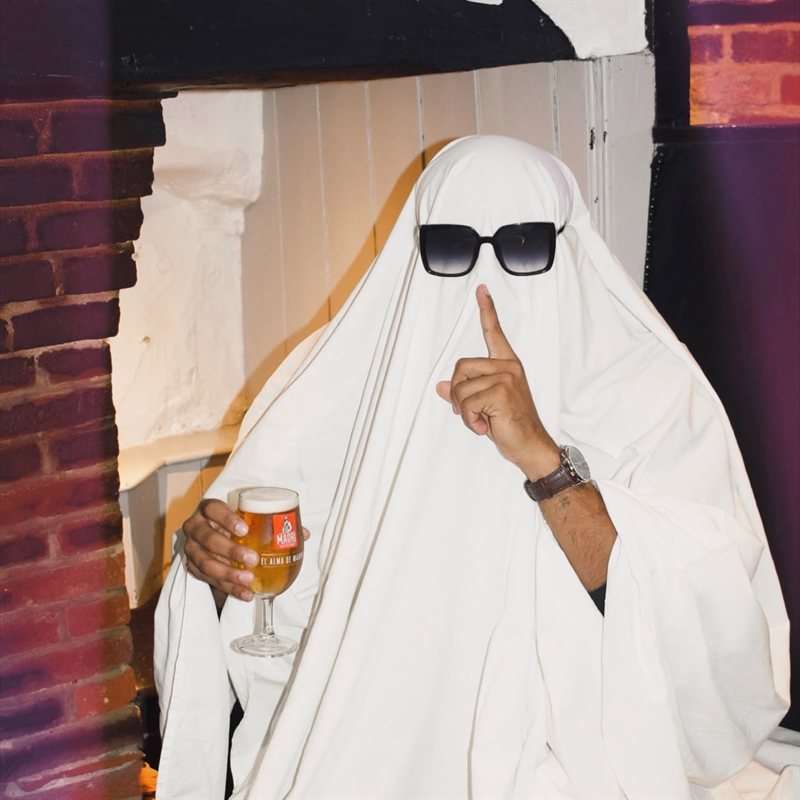 The ghost holding a pint with a finger to his lips